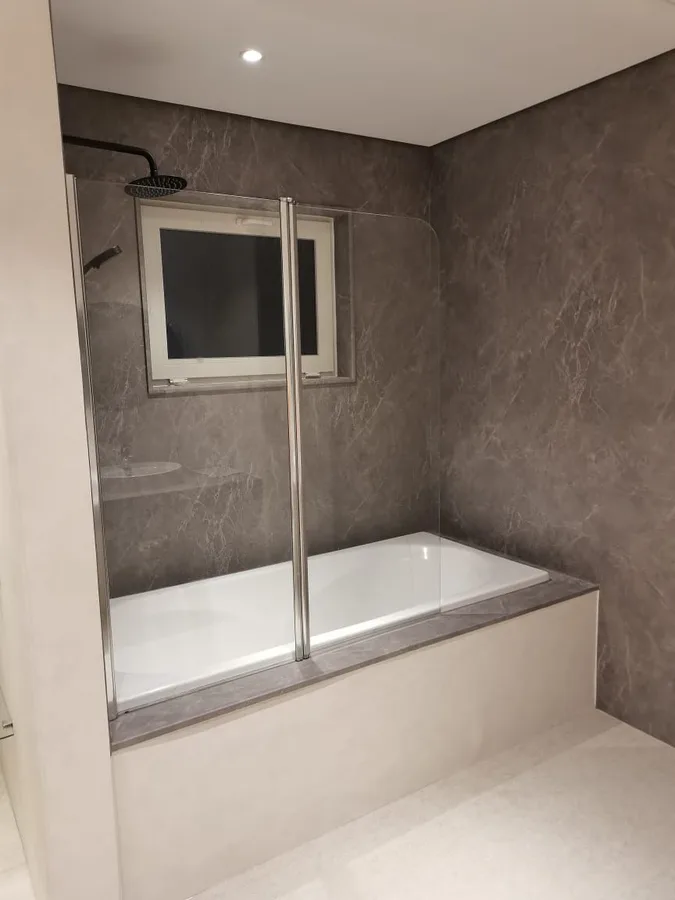 Framed glass bath screen fitted over a built-in bathtub