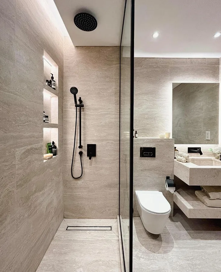 Glass shower screen beside a lit recessed niche